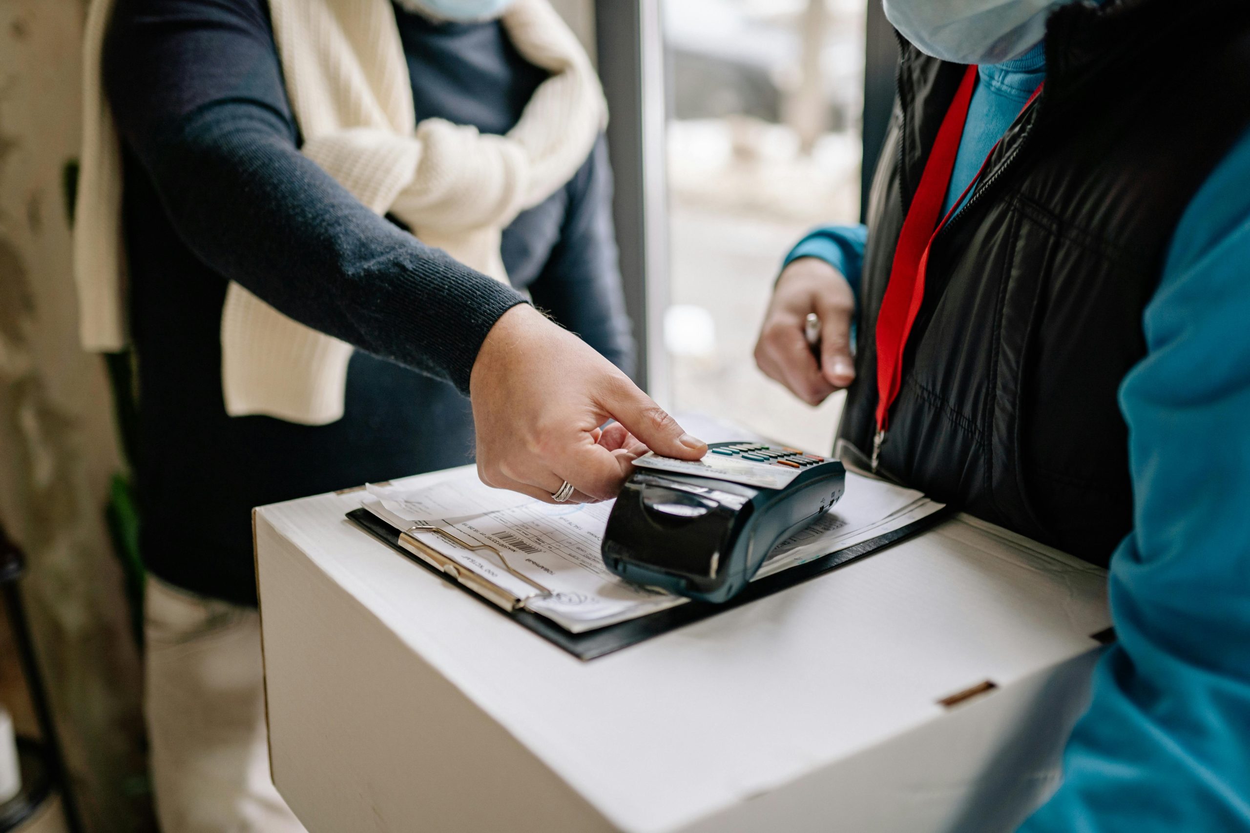 Person making a cashless payment for a package delivery using credit card and POS machine.