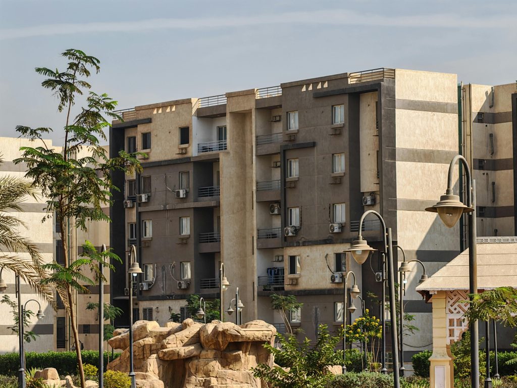 Urban residential buildings with landscaped gardens under a clear sky.